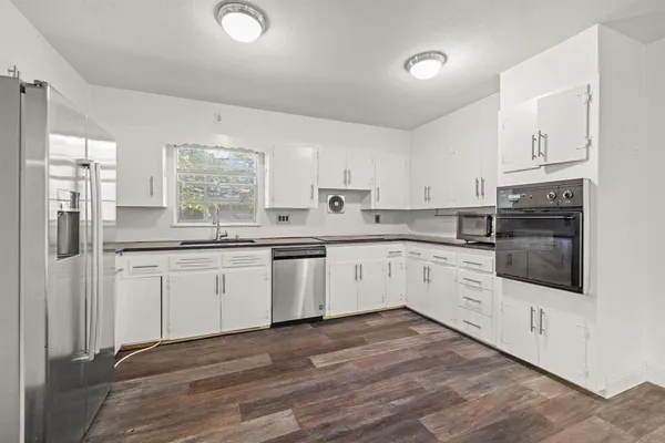 a kitchen with granite countertop white cabinets and white appliances