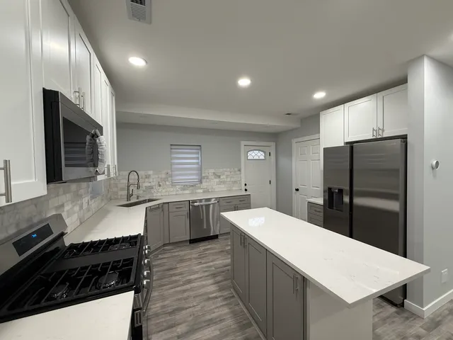 a kitchen with stainless steel appliances a sink a stove a refrigerator and cabinets