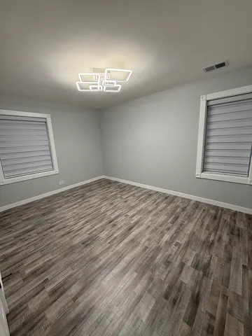 an empty room with wooden floor cabinet and windows