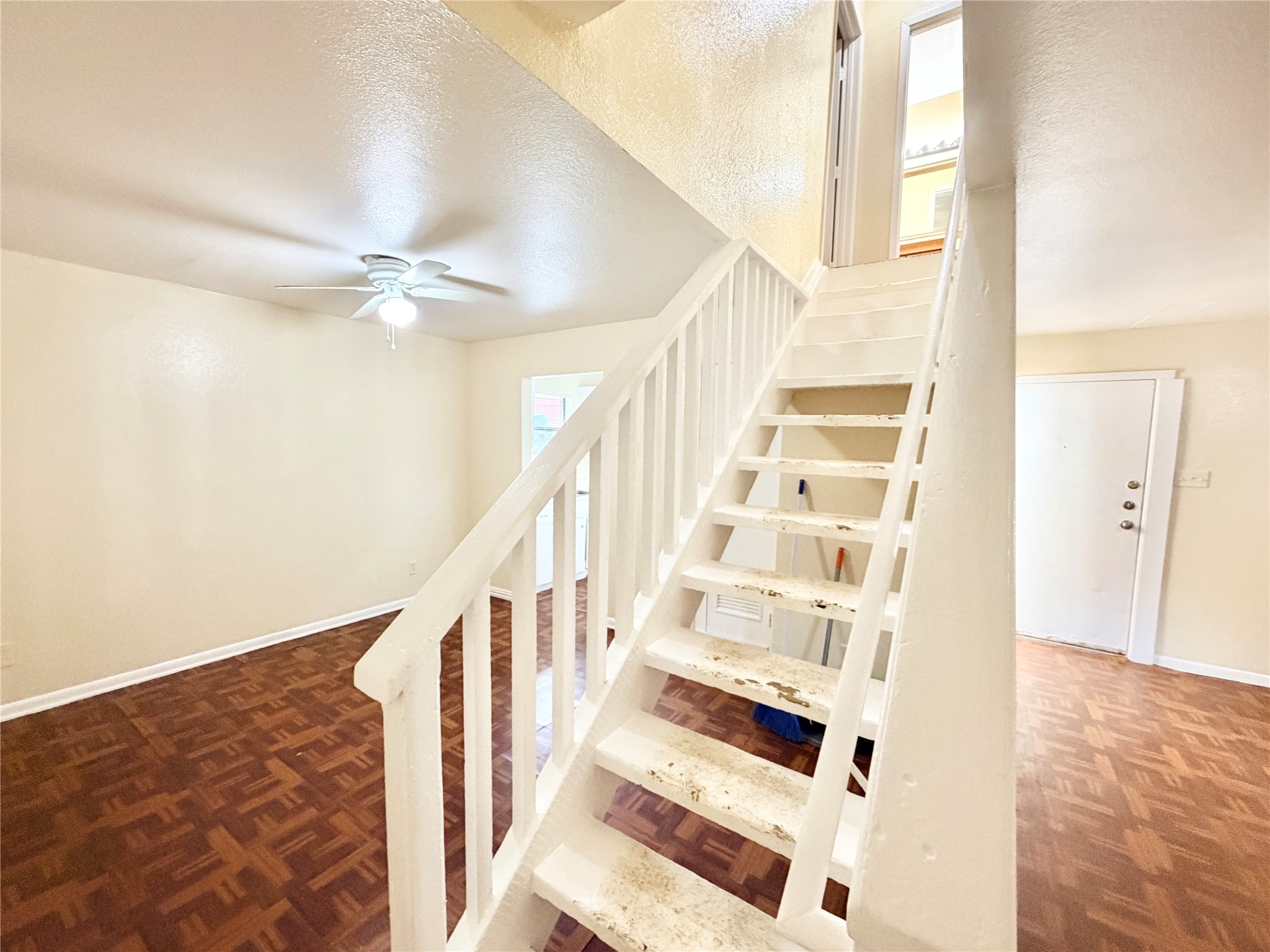 6257 Manor Road, Unit B Austin, TX 78723 - Photo 4 of 38 White painted staircase with balusters and handrail, textured walls, wood-finish flooring, white trim, and a ceiling fan with light fixture