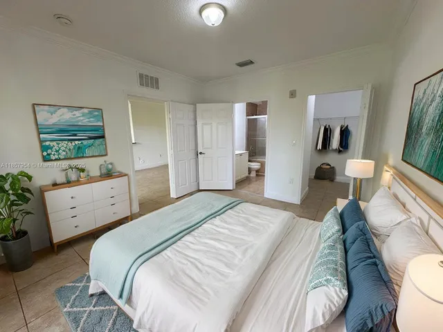 a bedroom with a bed and a flat tv screen on dresser