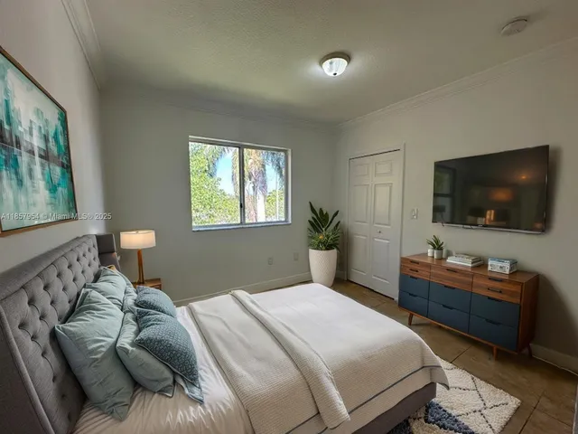 a bedroom with a bed and a flat tv screen on a dresser