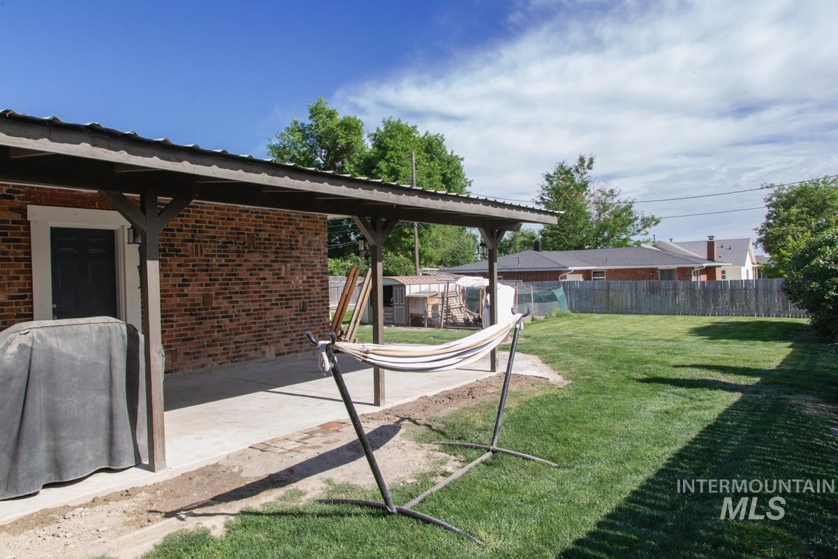 1404 Rochester Street Caldwell, ID 83605 - Photo 22 of 29 Expansive backyard featuring a manicured lawn, partial wood privacy fence, brick exterior, and a covered concrete patio with wood posts