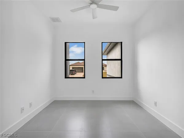 an empty room with windows and ceiling fan