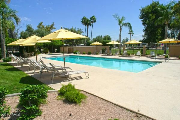 a view of a swimming pool with a table and chairs under an umbrella