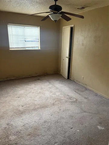 an empty room with a ceiling fan and a window