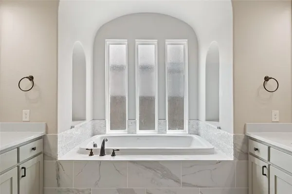 a spacious bathroom with a tub a double vanity sink and mirror