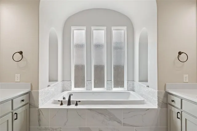 a spacious bathroom with a tub a double vanity sink and mirror