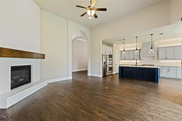 a living room with stainless steel appliances kitchen island a fireplace and wooden floor