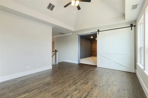 an empty room with wooden floor chandelier fan and windows