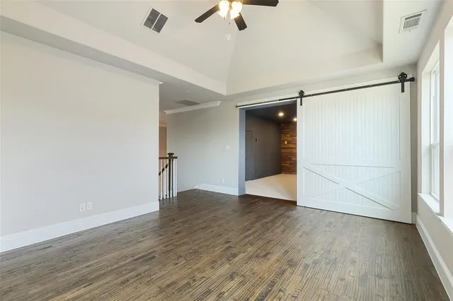 an empty room with wooden floor chandelier fan and windows