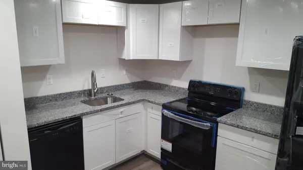 a kitchen with granite countertop stainless steel appliances white cabinets granite counter tops and a stove