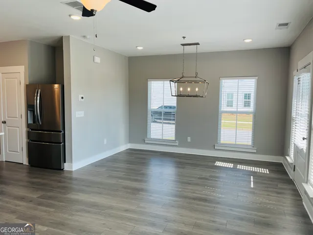 an empty room with wooden floor chandelier and windows