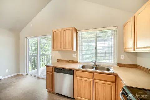 a kitchen with stainless steel appliances granite countertop a sink a stove a window and a counter space