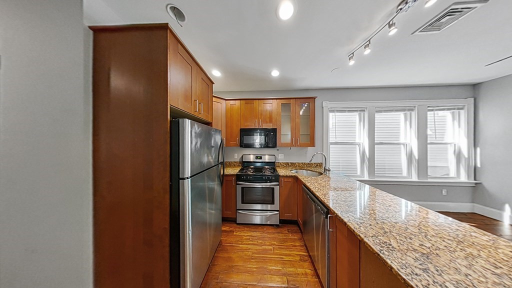 737 Parker Street, Unit 2 Boston, MA 02120 - Photo 2 of 12 a kitchen with stainless steel appliances granite countertop a refrigerator and stove
