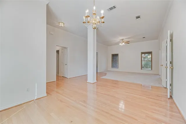 a view of an empty room with a chandelier fan