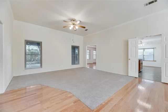 a view of an empty room with wooden floor and a window