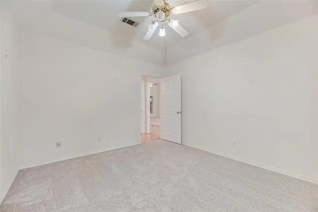 an empty room with a chandelier fan and closet area