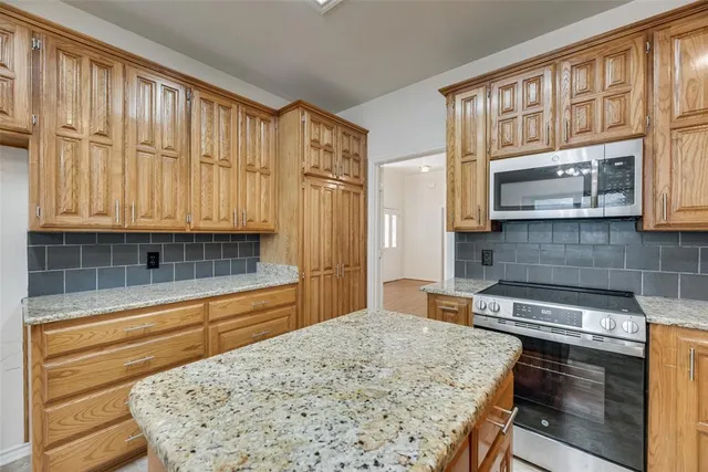 a kitchen with stainless steel appliances kitchen island granite countertop a refrigerator and cabinets