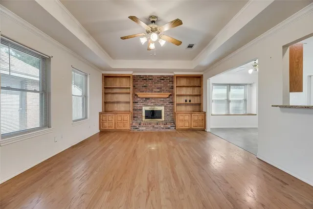 an empty room with wooden floor fireplace and windows