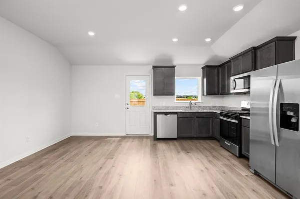 a large kitchen with a wooden floor stainless steel appliances and cabinets