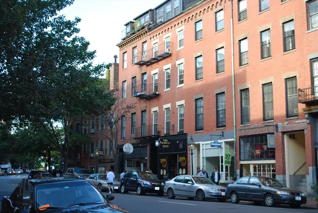 a city street lined with tall buildings and cars parked in front of it