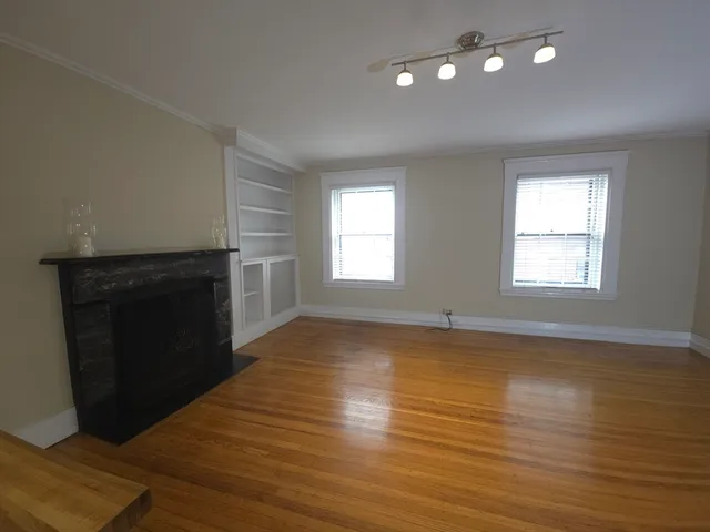 a view of an empty room with window and wooden floor