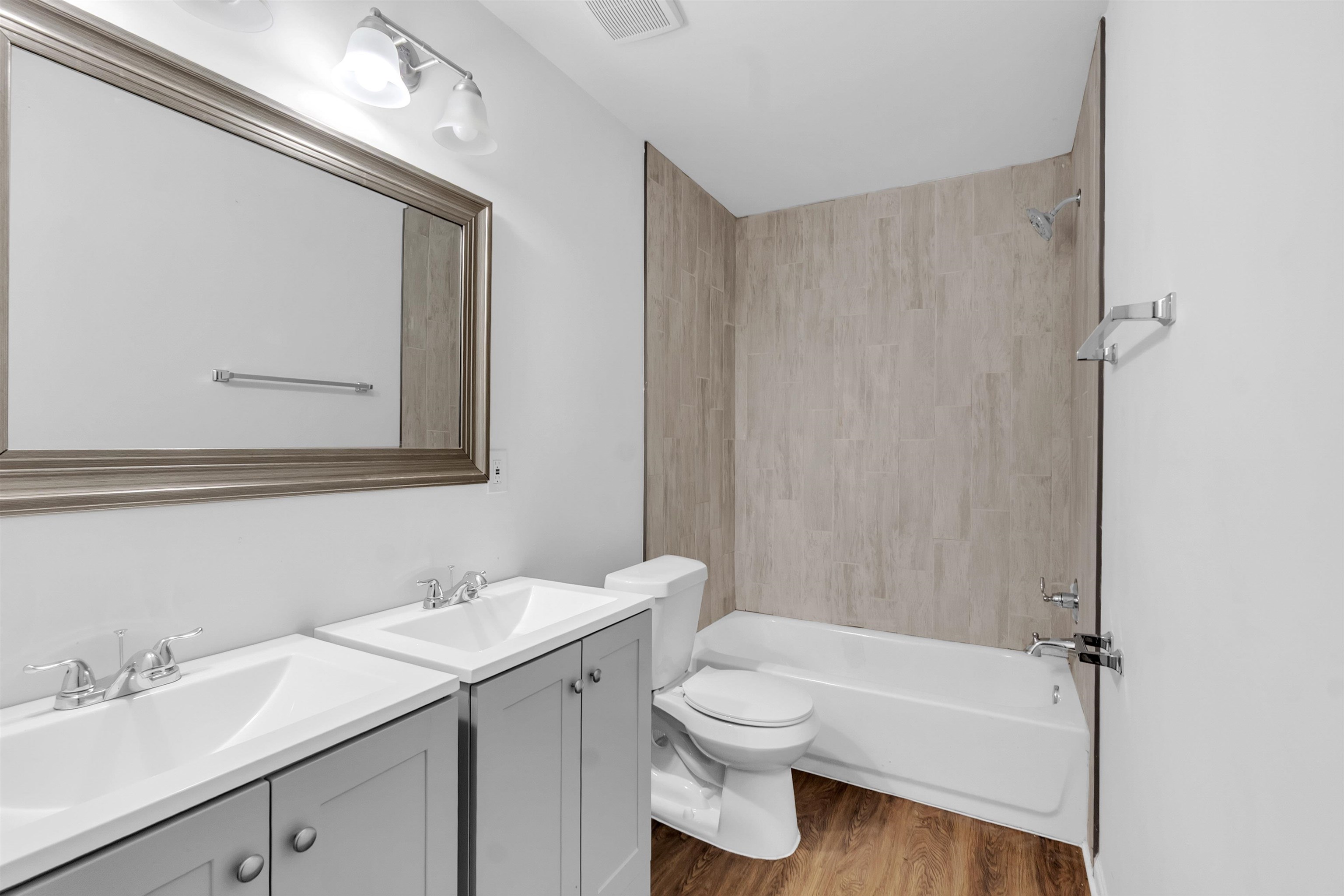 3021 Chelsea Avenue Memphis, TN 38108 - Photo 6 of 17 Full bathroom with two vanities, washtub / shower combination, and light wood-type flooring