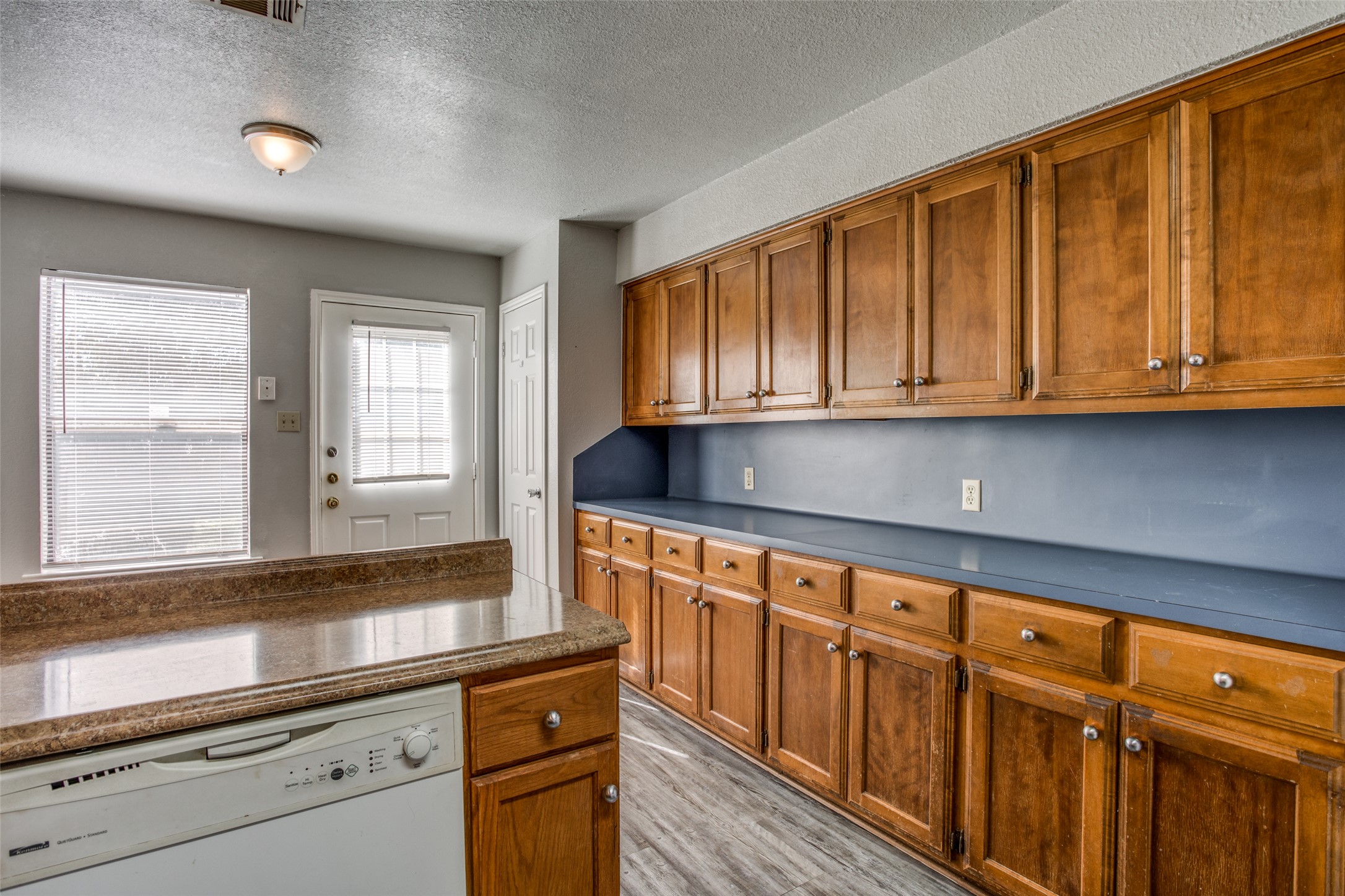 106 Verna Spur, Unit B Georgetown, TX 78628 - Photo 11 of 25 A functional kitchen features wood cabinetry, durable countertops, and an integrated dishwasher.