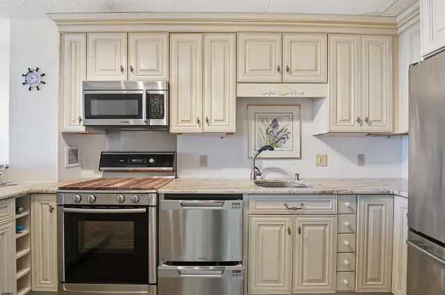 a kitchen with granite countertop white cabinets and stainless steel appliances