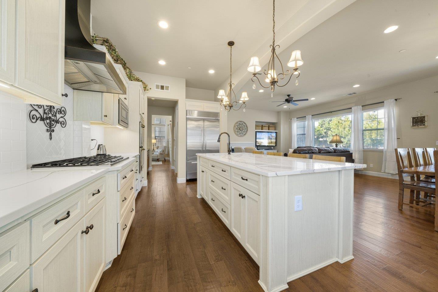3943 Vía Cristobal Campbell, CA 95008 - Photo 17 of 59 a large white kitchen with a large island oven a stove a dining table and chairs with wooden floor