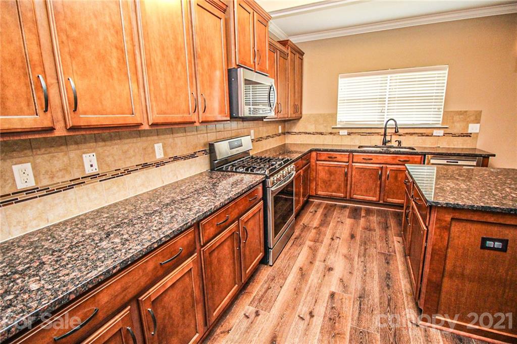 7042 Meyer Road Fort Mill, SC 29715 - Photo 6 of 18 a kitchen with stainless steel appliances granite countertop a sink stove and cabinets