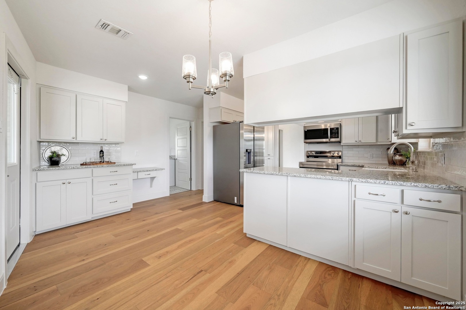 935 Spring Branch Road Spring Branch, TX 78070 - Photo 12 of 48 a large white kitchen with kitchen island a sink dishwasher a stove and white cabinets with wooden floor