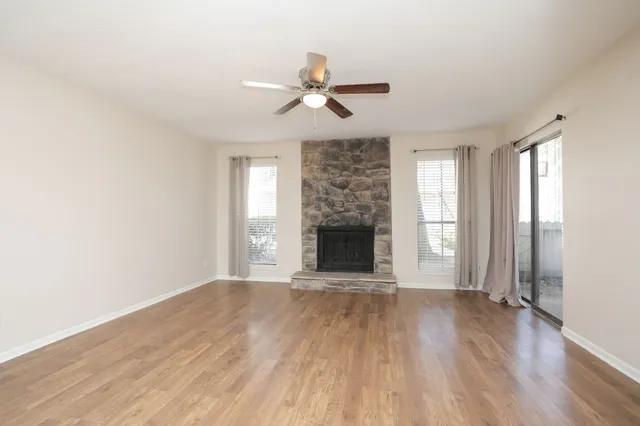 a view of an empty room with window and wooden floor