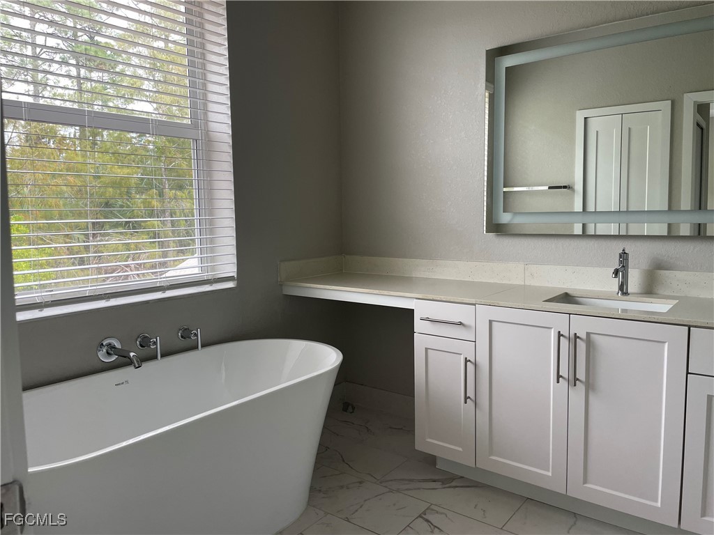 7081 Venice Way, Unit 1804 Naples, FL 34119 - Photo 6 of 12 a bathroom with a bathtub a sink a vanity and a window