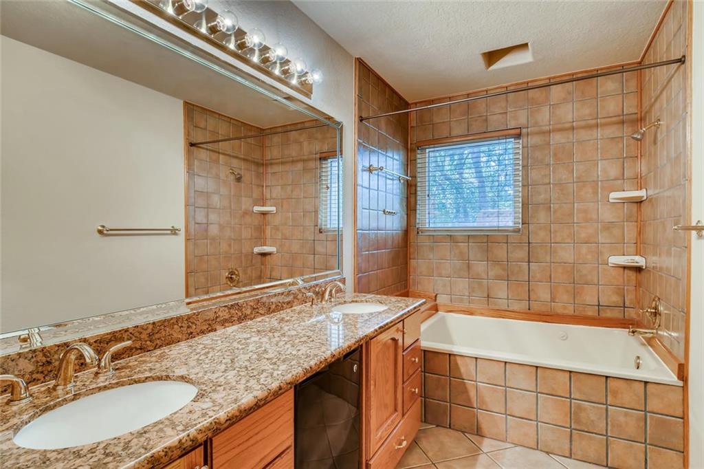 1600 Whitney Way Austin, TX 78741 - Photo 16 of 26 Bathroom with tiled shower / bath, double vanity, light tile patterned floors, and a textured ceiling