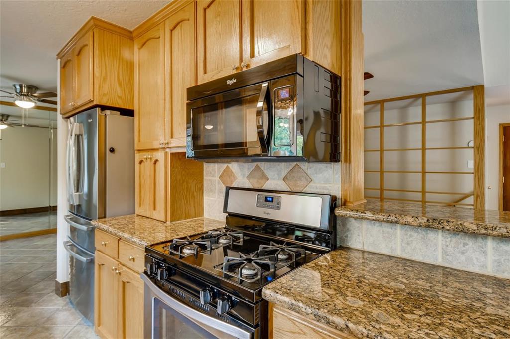 1600 Whitney Way Austin, TX 78741 - Photo 6 of 26 Kitchen with appliances with stainless steel finishes, a ceiling fan, light stone countertops, backsplash, and light brown cabinets