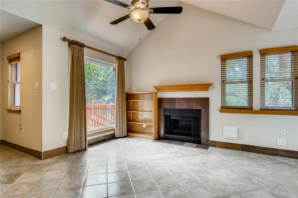 1600 Whitney Way Austin, TX 78741 - Photo 10 of 26 Unfurnished living room with a tile fireplace, light tile patterned flooring, a ceiling fan, and high vaulted ceiling