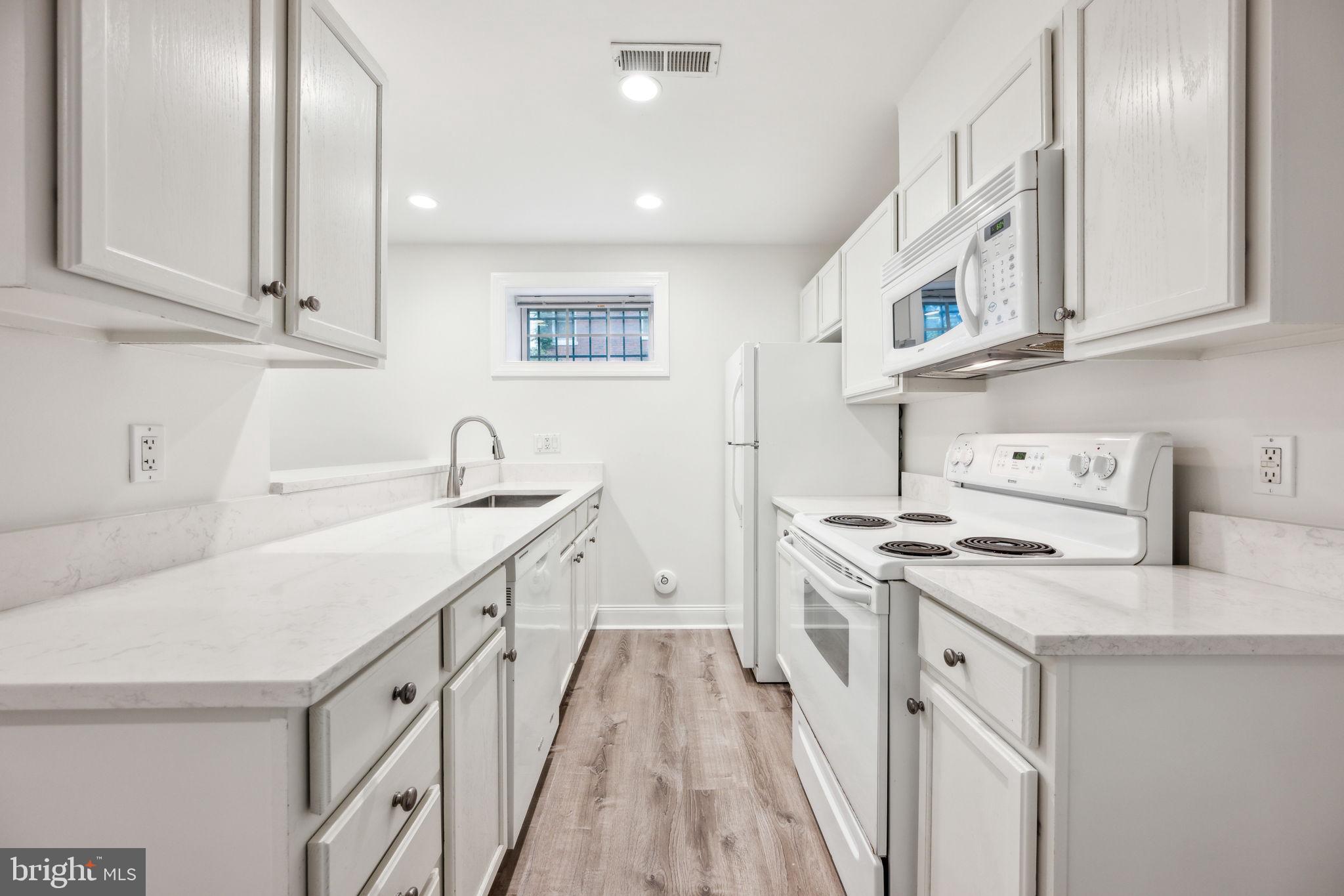 2444 Tunlaw Road Northwest Washington, DC 20007 - Photo 32 of 38 a kitchen with a sink stove and cabinets