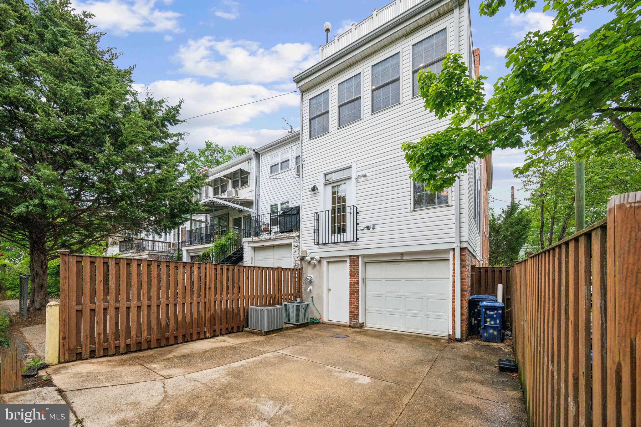 2444 Tunlaw Road Northwest Washington, DC 20007 - Photo 38 of 38 a view of a white house with large trees and wooden fence