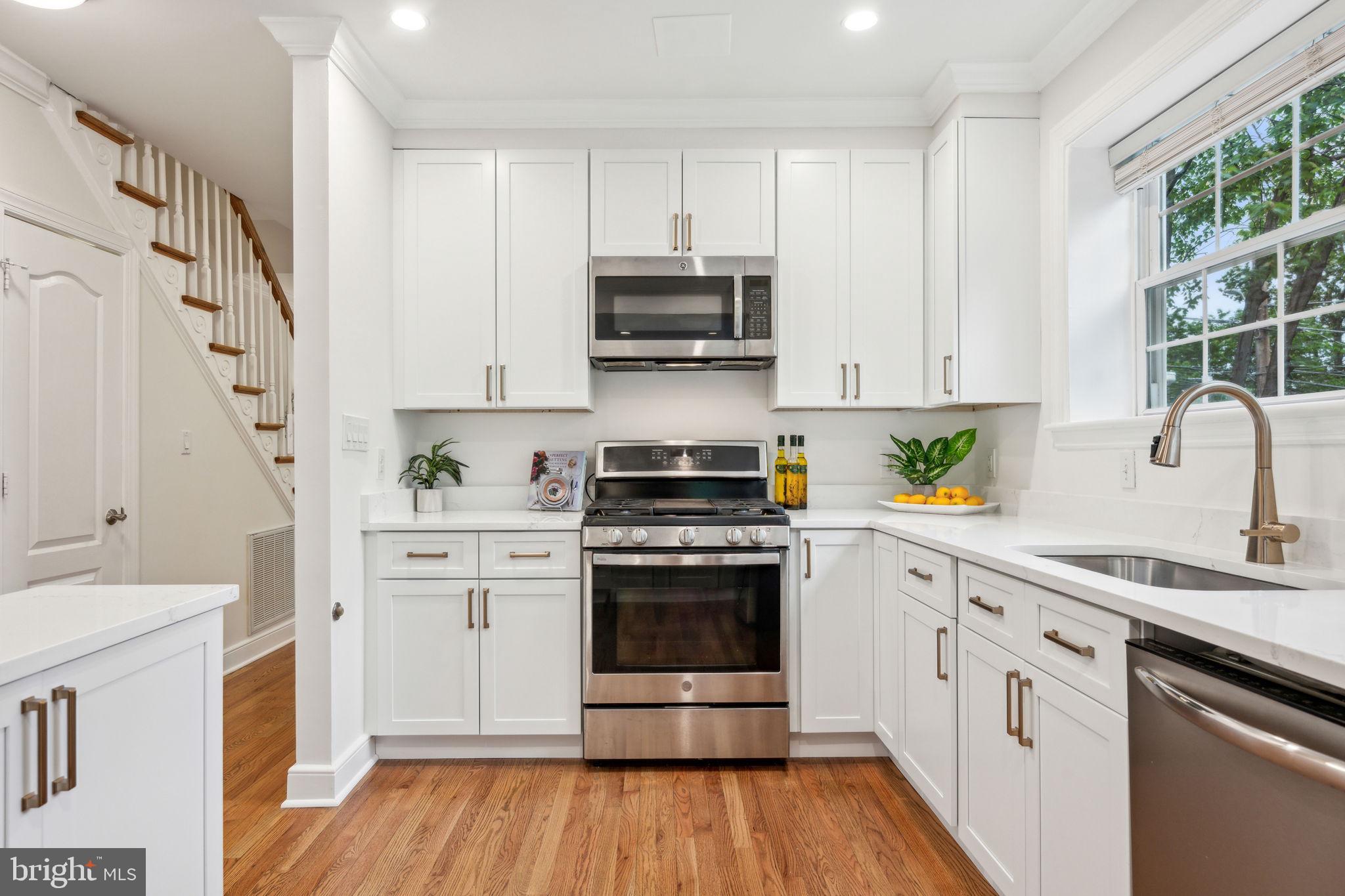 2444 Tunlaw Road Northwest Washington, DC 20007 - Photo 6 of 38 a kitchen with stainless steel appliances a stove sink and cabinets