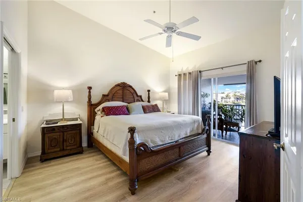 a spacious bedroom with a bed a chandelier with a flat tv screen and dresser