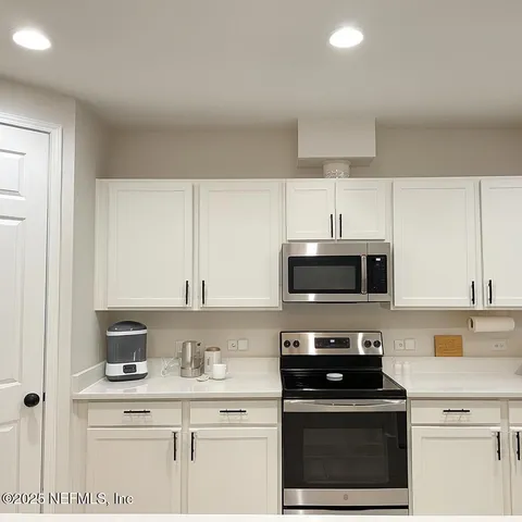 a kitchen with granite countertop a stove a microwave a sink and cabinets