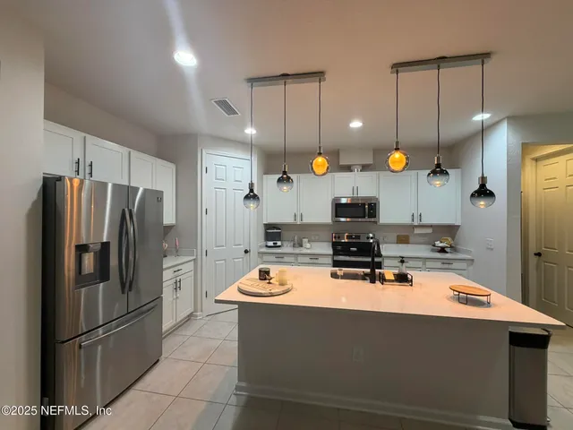 a room with stainless steel appliances kitchen island a table and chairs