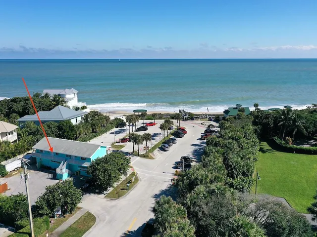 an aerial view of ocean and residential houses with outdoor space