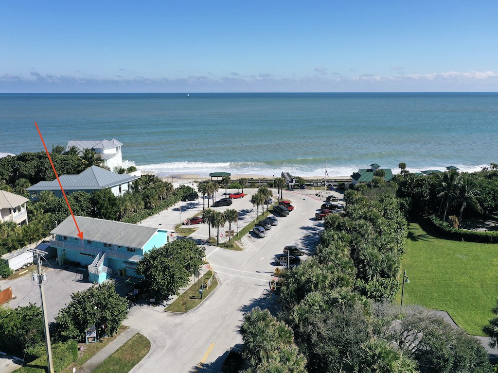 an aerial view of ocean and residential houses with outdoor space