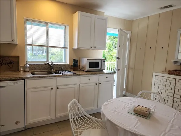 a kitchen with stainless steel appliances granite countertop a sink a stove a microwave cabinets and a dining table