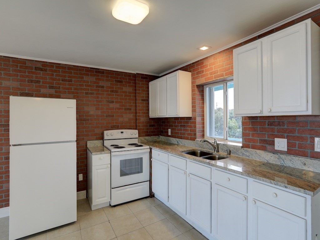 1840 Wabasso Beach Road Vero Beach, FL 32963 - Photo 10 of 22 a kitchen with granite countertop white cabinets and white appliances