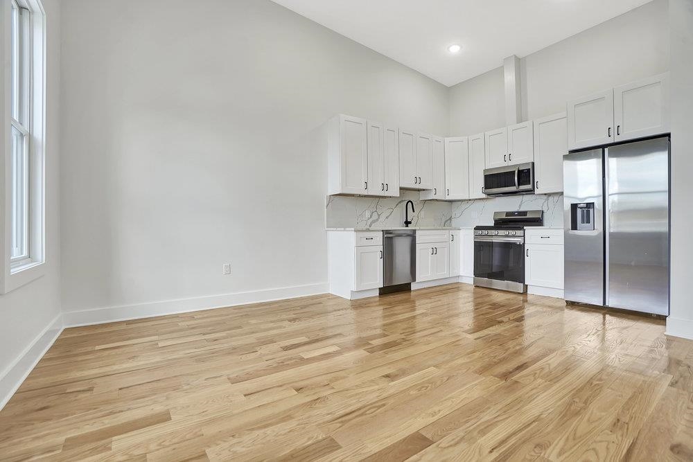 34 Van Reypen Street, Unit 2 Jersey City, NJ 07306 - Photo 9 of 25 a kitchen with wooden floors and stainless steel appliances