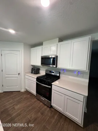 a kitchen with granite countertop white cabinets and white appliances